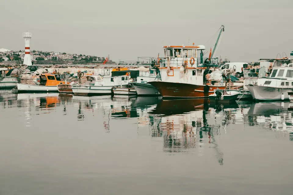 Limanda durgun su, teknelerin yansıması. Rüzgâr çıkmadan önceki o yarım saat.